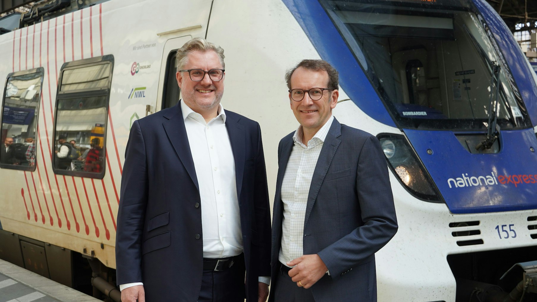 Tobias Krogmann und Michael Hetzer (rechts), die Geschäftsführer des Eisenbahnverkehrsunternehmens National Express, stehen im Juli 2025 vor einem Regionalzug im Kölner Hauptbahnhof.