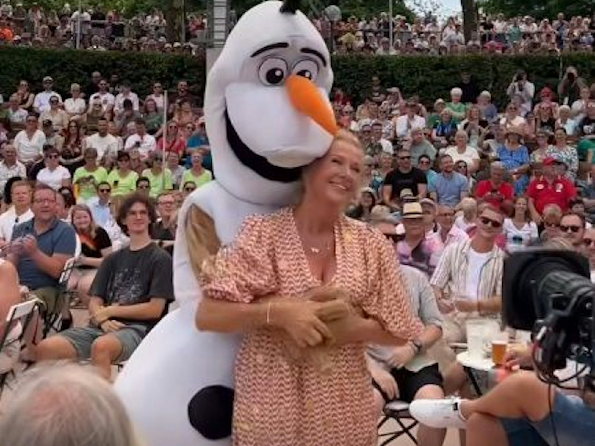 Eine Schneemann-Figur umarmt von hinten eine Frau.