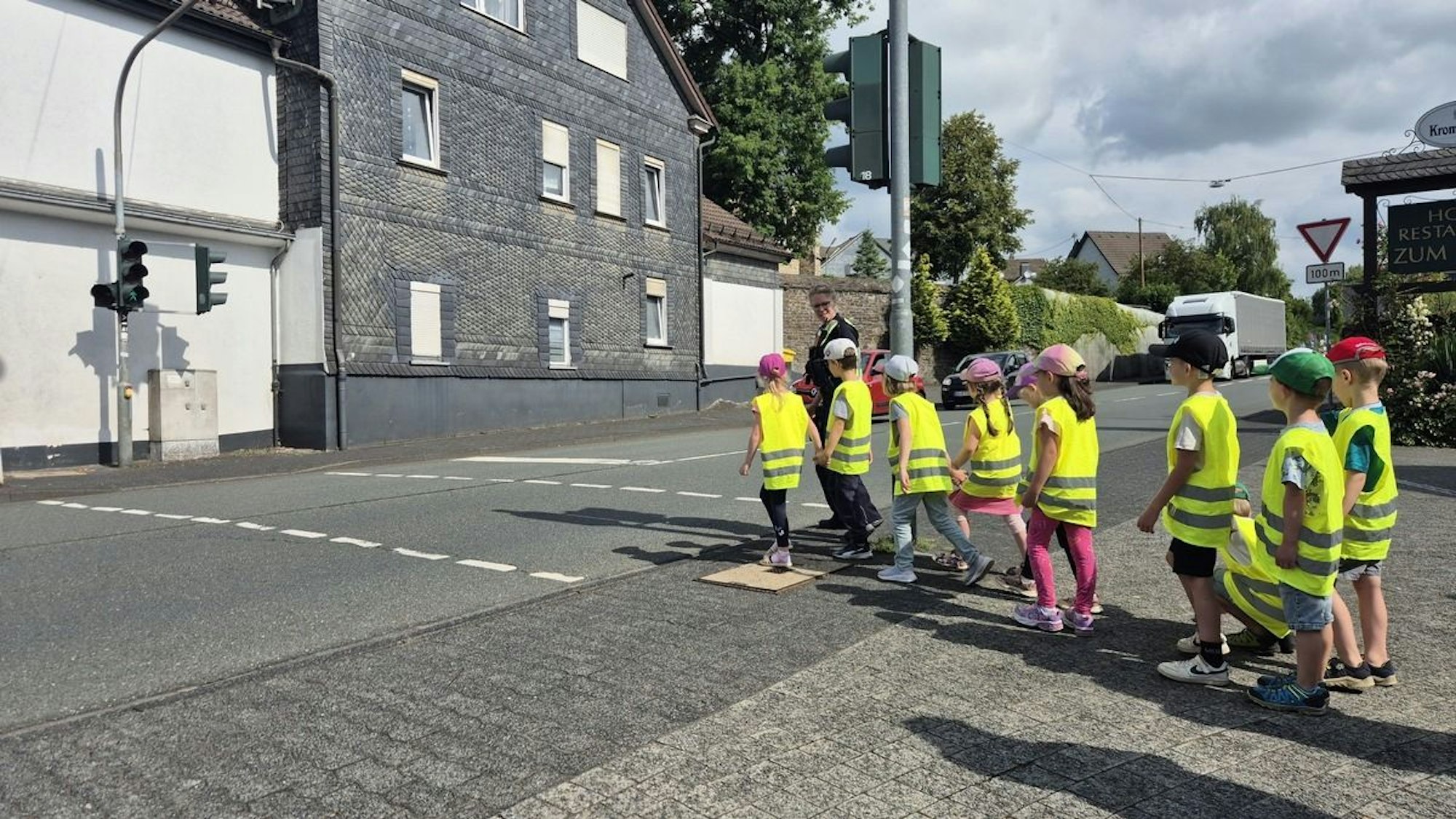 Polizist erklärt Kindern das richtige Verhalten am Zebrastreifen.
