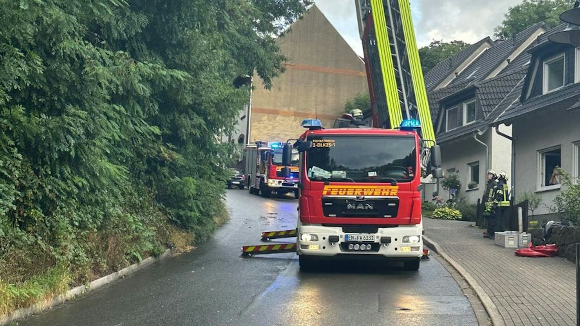 Ein Baum ist in einem Hang umgeknickt und wird von der Feuerwehr mit einer Drehleiter gesichert.