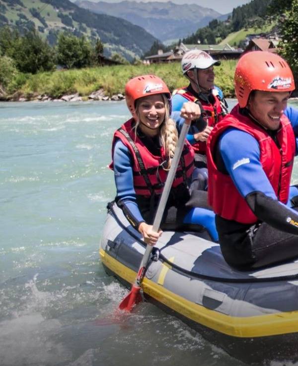 Fünf Personen paddeln in einem Boot über einen Fluss