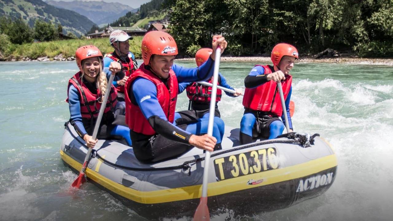 Fünf Personen paddeln in einem Boot über einen Fluss