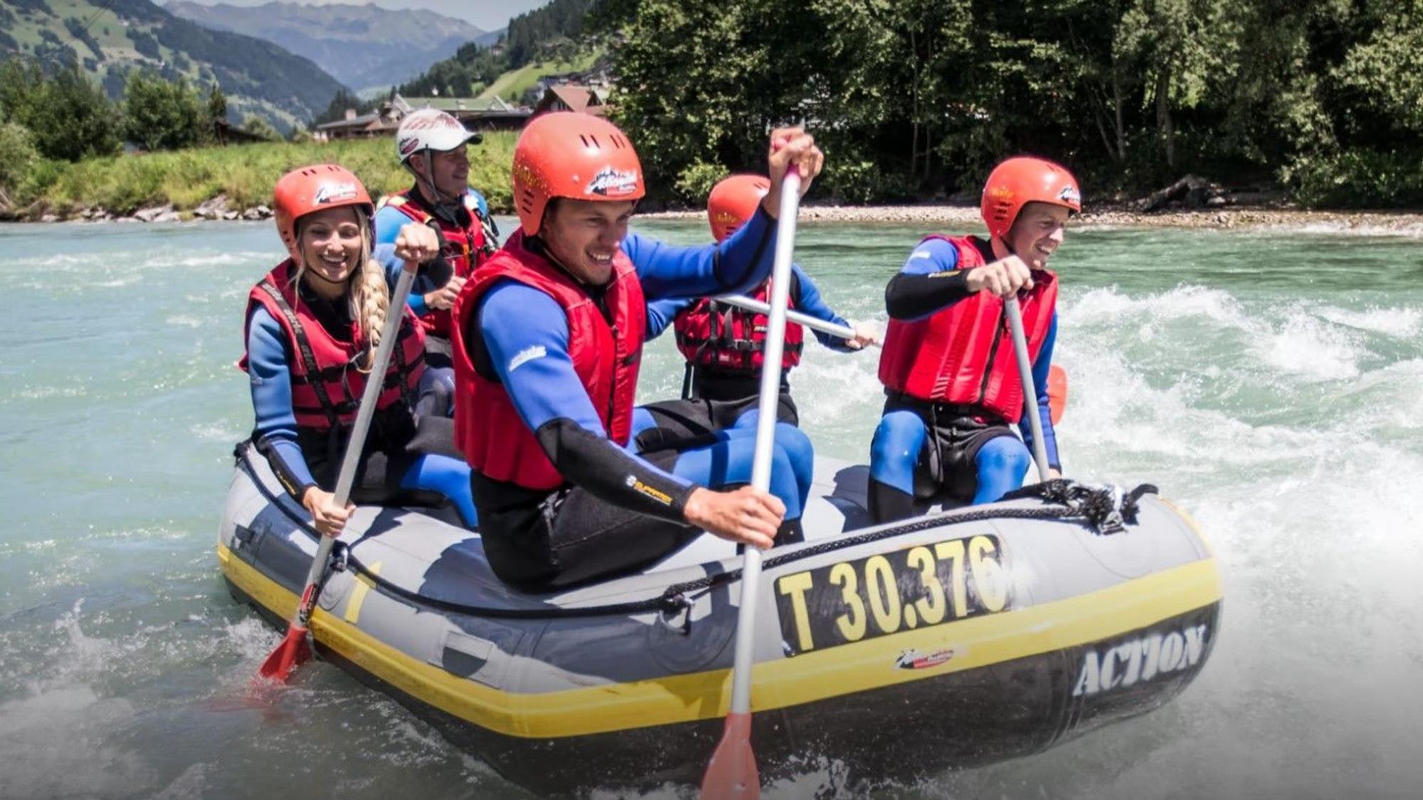 Fünf Personen paddeln in einem Boot über einen Fluss