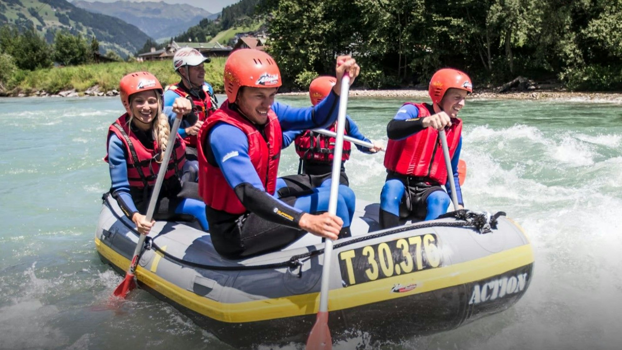 Fünf Personen paddeln in einem Boot über einen Fluss