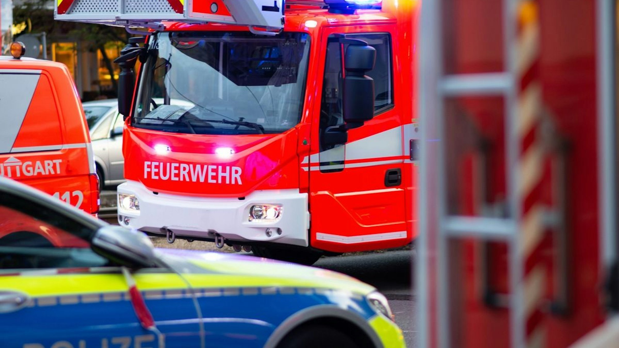 Ein Feuerwehrauto steht an einem Waldrand, wo es brennt.