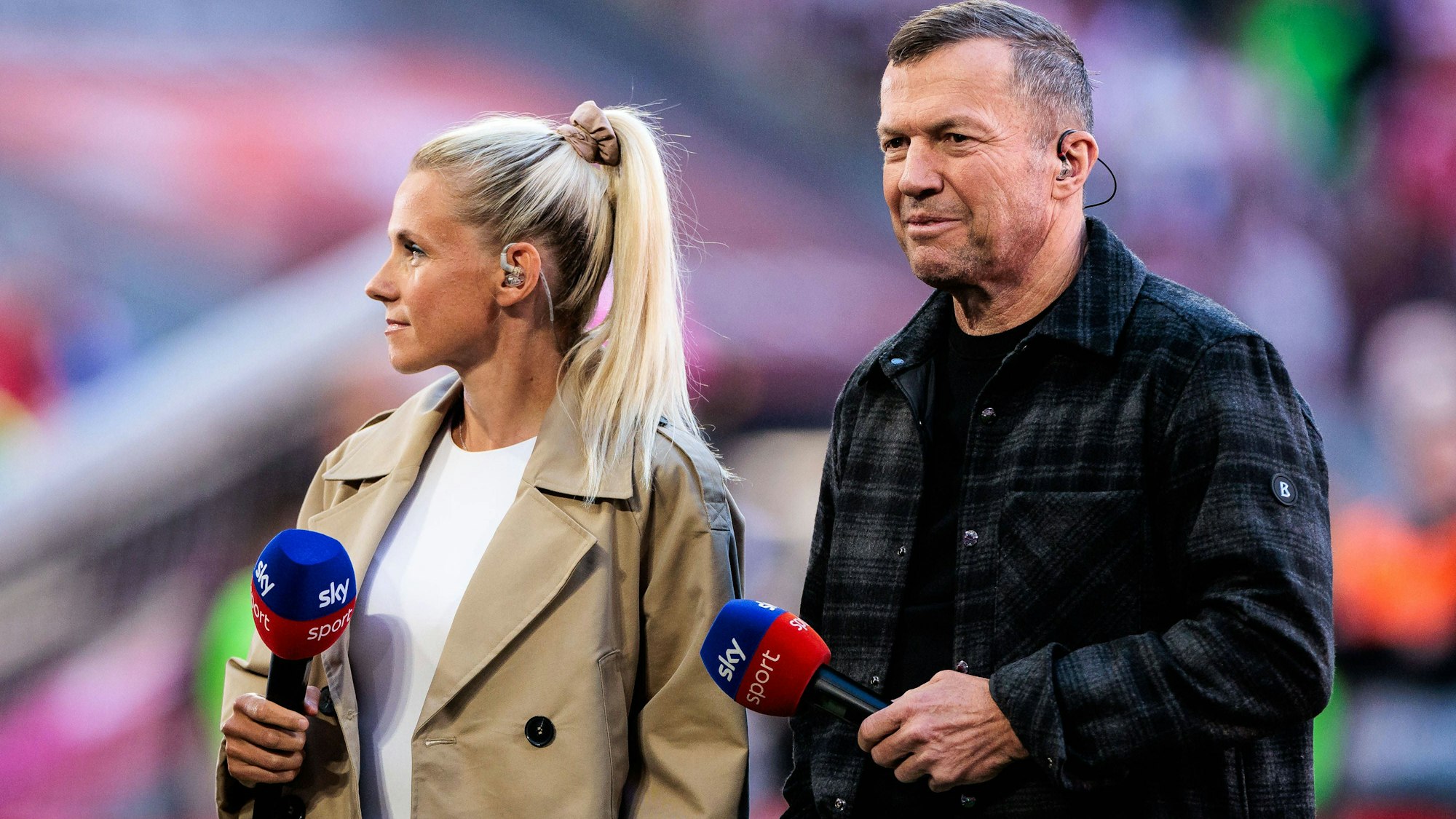 Lothar Matthäus und Julia Simic warten mit Sky-Mikros in der Hand auf ihren Einsatz.