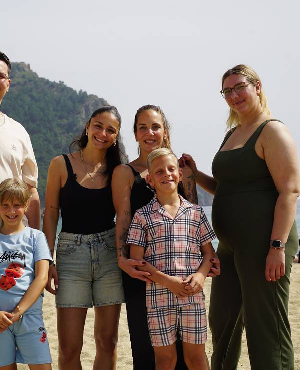 Eine Frau steht mit ihren vier Kindern am Strand.