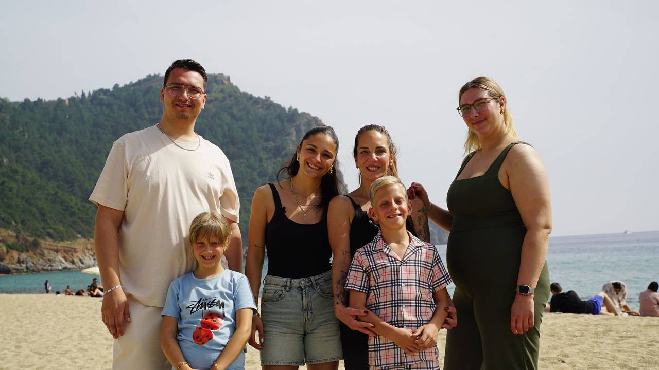 Eine Frau steht mit ihren vier Kindern am Strand.