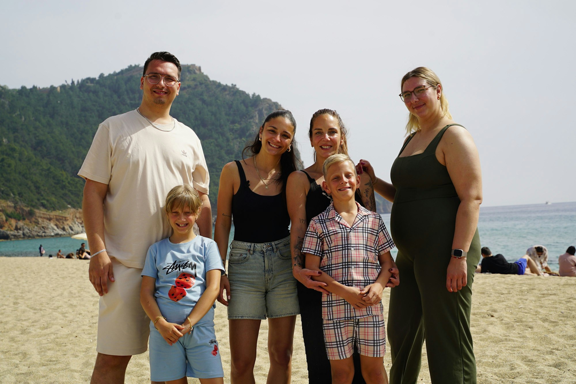Eine Frau steht mit ihren vier Kindern am Strand.
