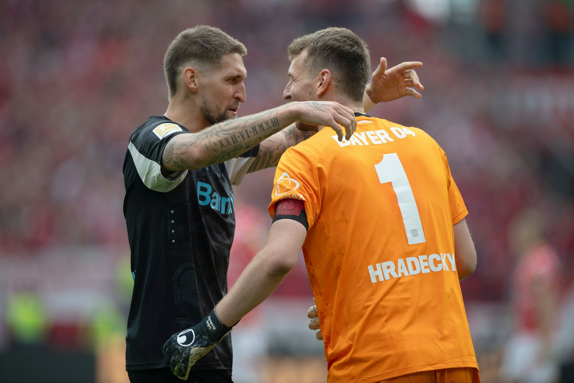 Robert Andrich und Lukas Hradecky umarmen sich jubelnd.