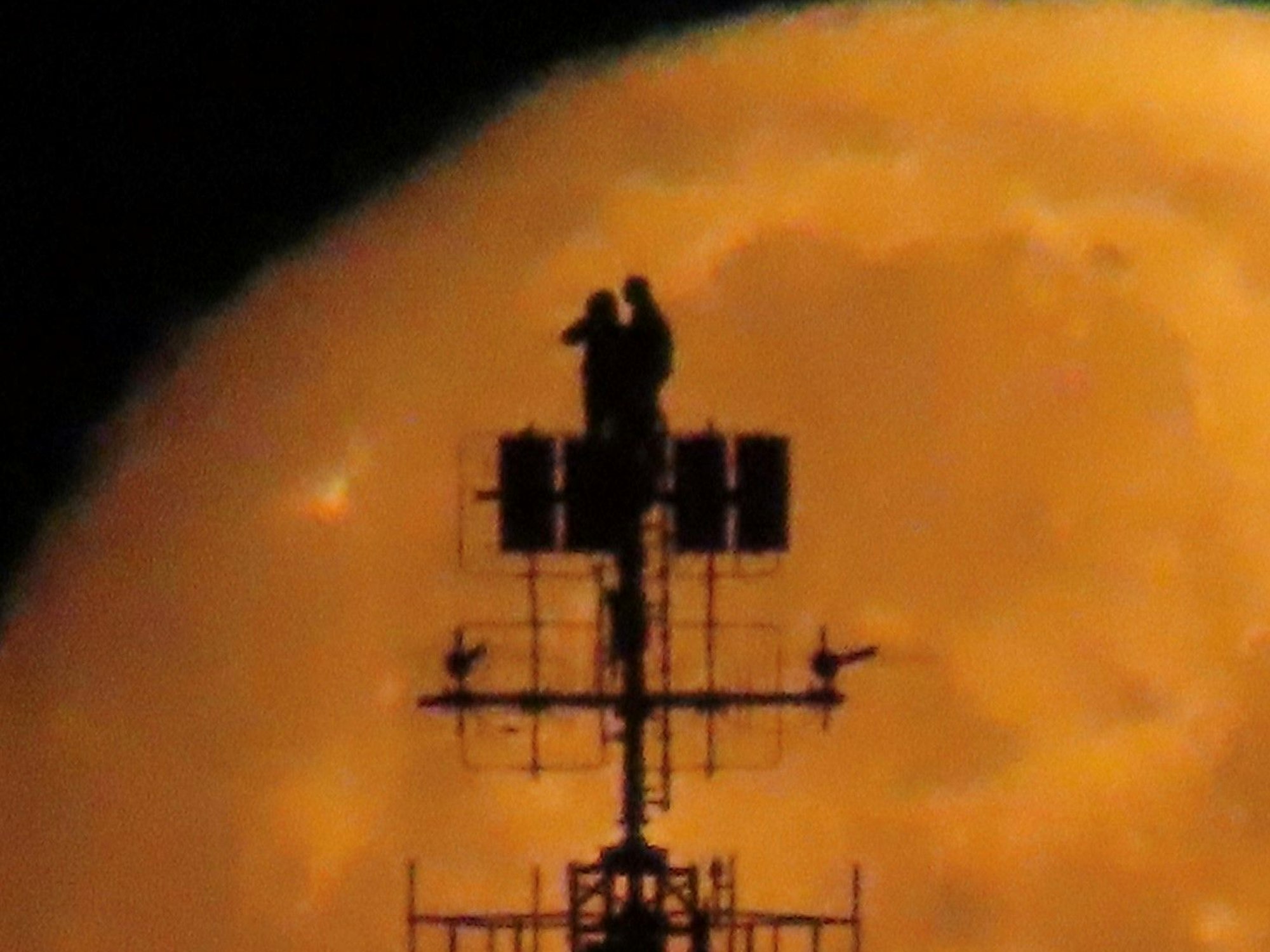 Zwei Personen stehen auf der Antennen-Konstruktion eines Gebäudes in Köln.