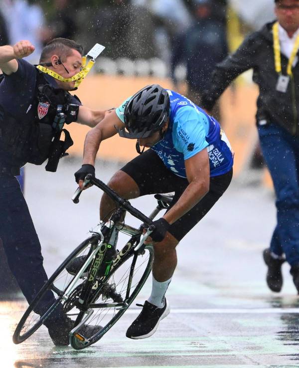 Ein Sicherheitsmann stößt einen Radfahrer im Ziel der Tour de France zu Boden.