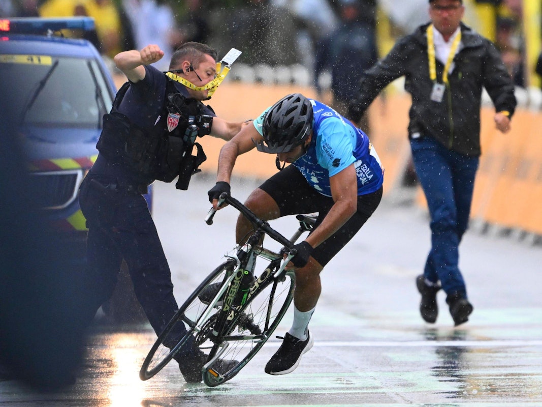 Ein Sicherheitsmann stößt einen Radfahrer im Ziel der Tour de France zu Boden.