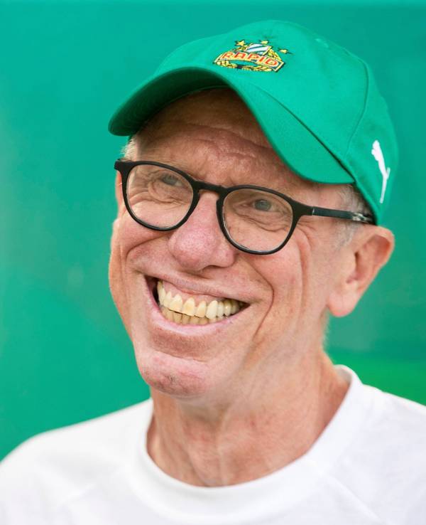 Peter Stöger lächelt mit Rapid-Kappe in die Kamera.