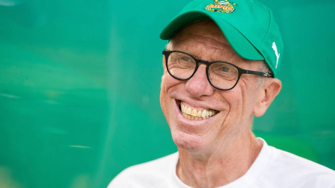 Peter Stöger lächelt mit Rapid-Kappe in die Kamera.