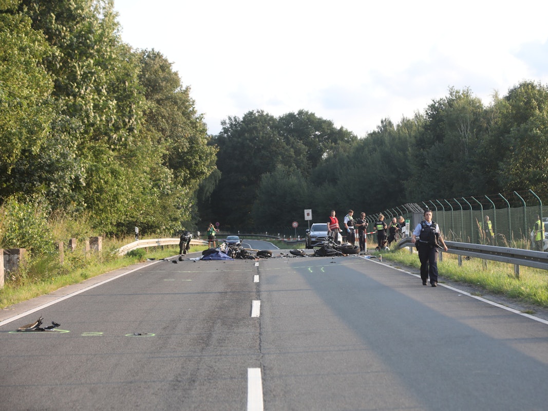 Polizeikräfte sind an einer Straße im Einsatz, auf der Fahrbahn liegen Trümmerteile.