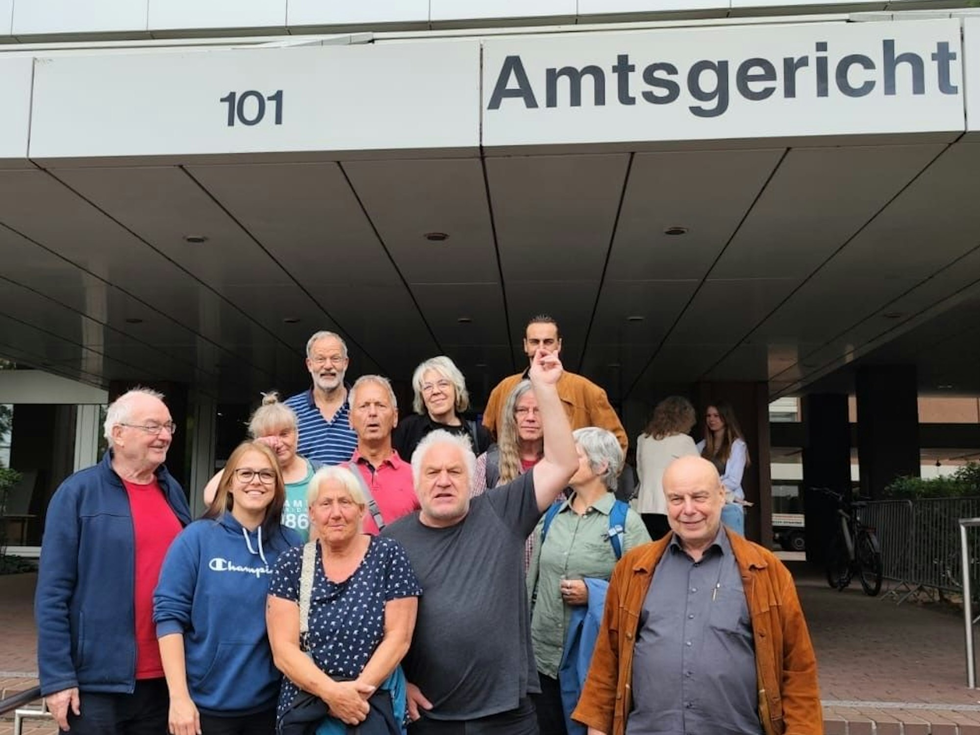 Eine Gruppe Männer und Frauen steht vor einem Amtsgericht.