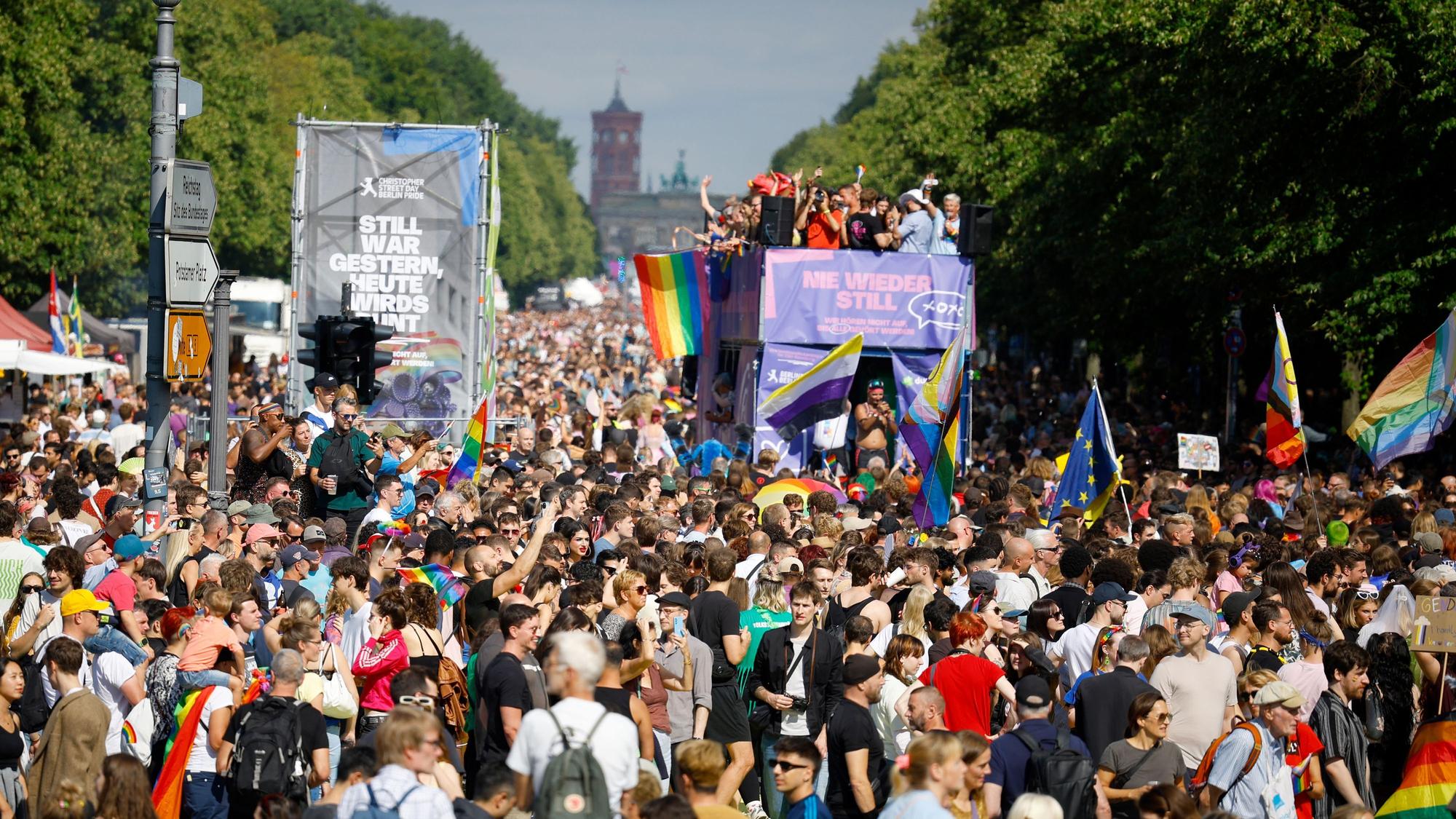 Menschenmassen drängen sich beim CSD, mittendrin ein Umzugswagen, auf dem Menschen feiern.