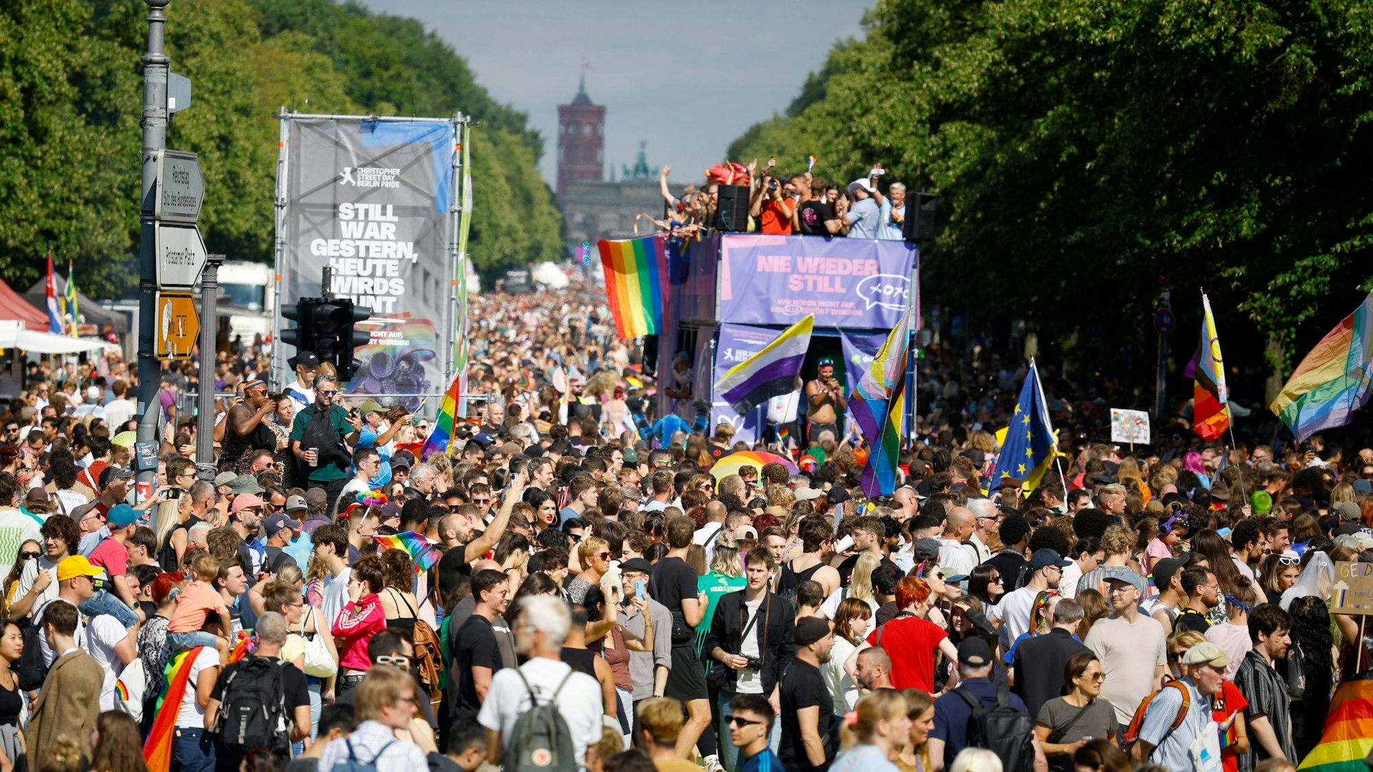 Menschenmassen drängen sich beim CSD, mittendrin ein Umzugswagen, auf dem Menschen feiern.