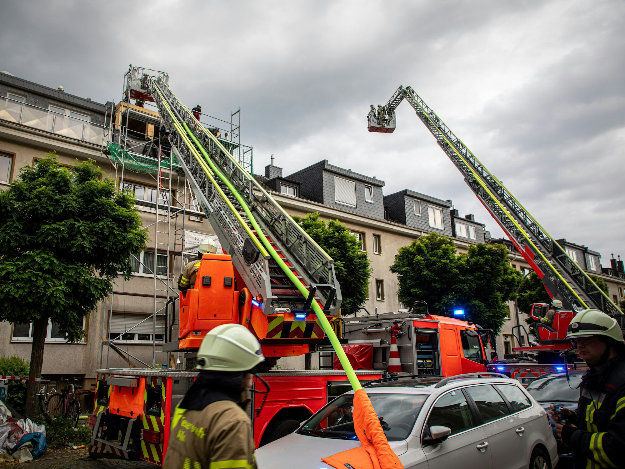 Vor einer Häuserreihe stehen Einsatzkräfte und -fahrzeuge der Feuerwehr, zwei Drehleitern sind ausgefahren.