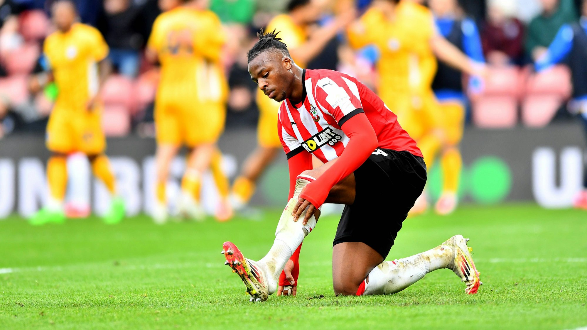 Armel Bella-Kotchap zieht sich bei einem Spiel den Schuh neu an.