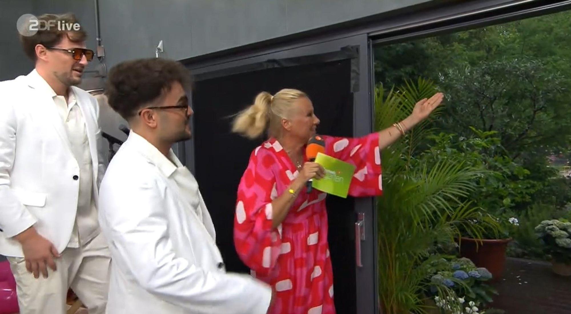 Schaut euch das an! Andrea Kiewel zeigt „Malle Anja“ den prasselnden Regen. Der ZDF-„Fernsehgarten“ musste kurzfristig aus dem Studio gesendet werden.