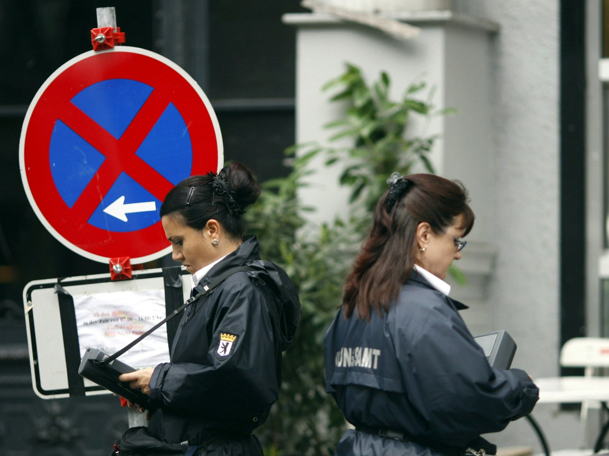 Zwei Politessen schreiben in Berlin die Kennzeichen von Autos auf, die im absoluten Halteverbot stehen.