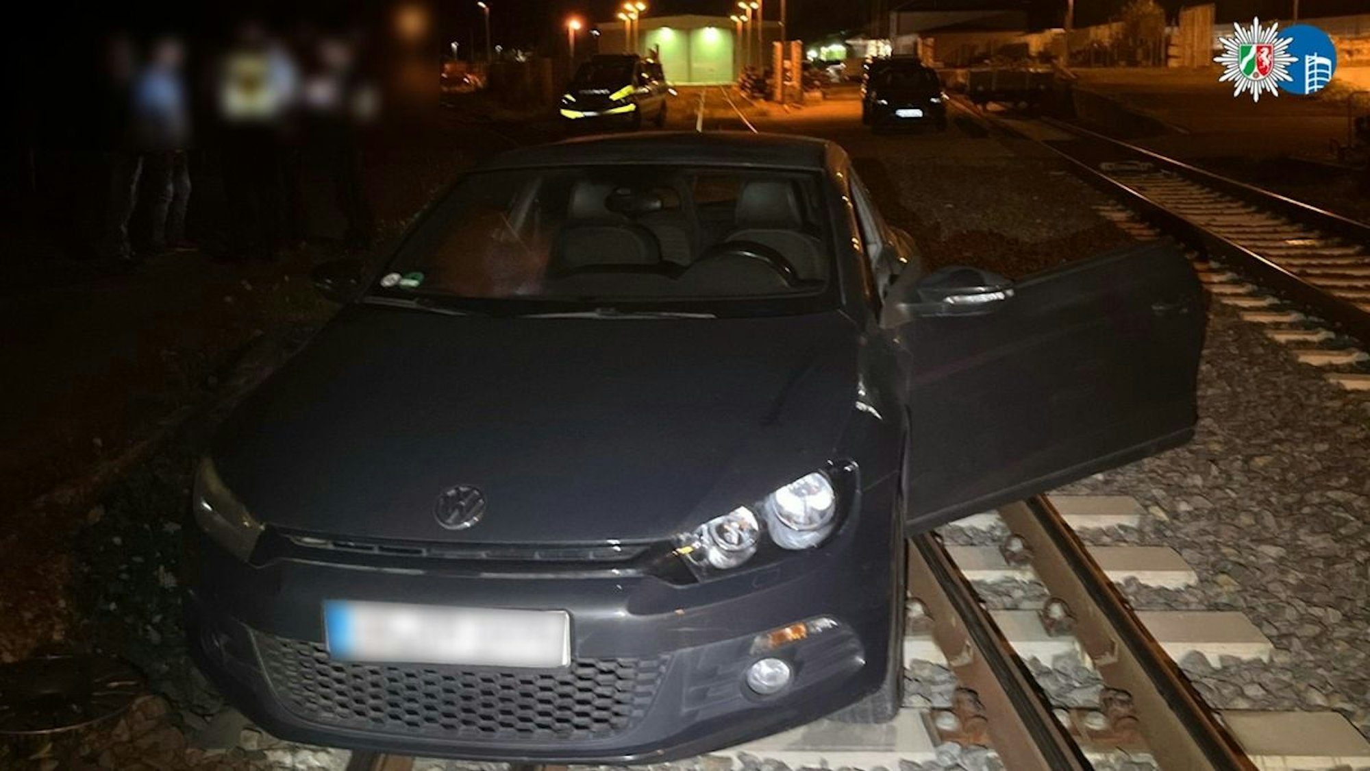 Ein VW Scirocco, der auf Bahngleisen feststeckt.