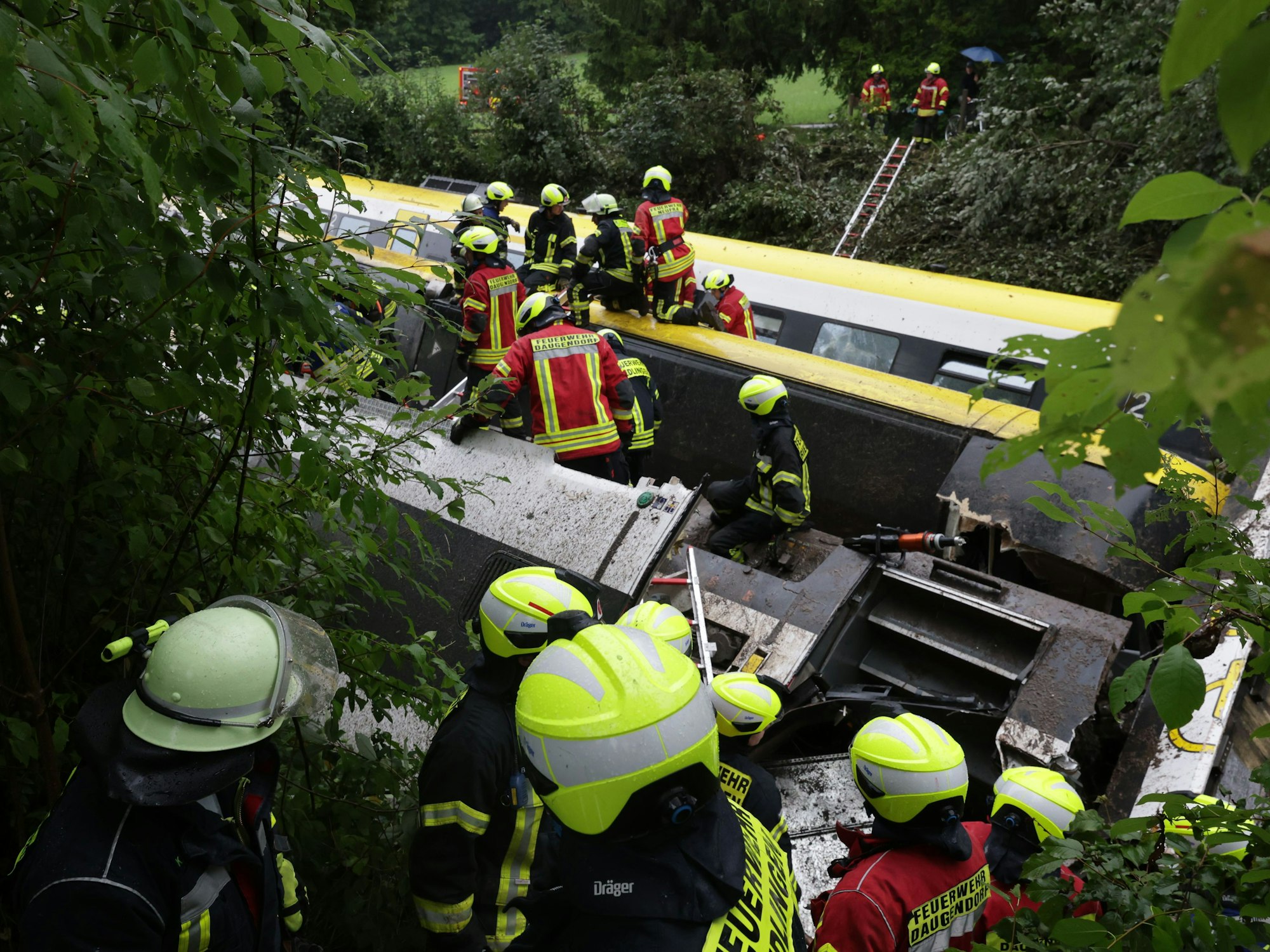 Waggons des entgleisten Zuges liegen auf der Seite. Einsatzkräfte suchen nach Fahrgästen.