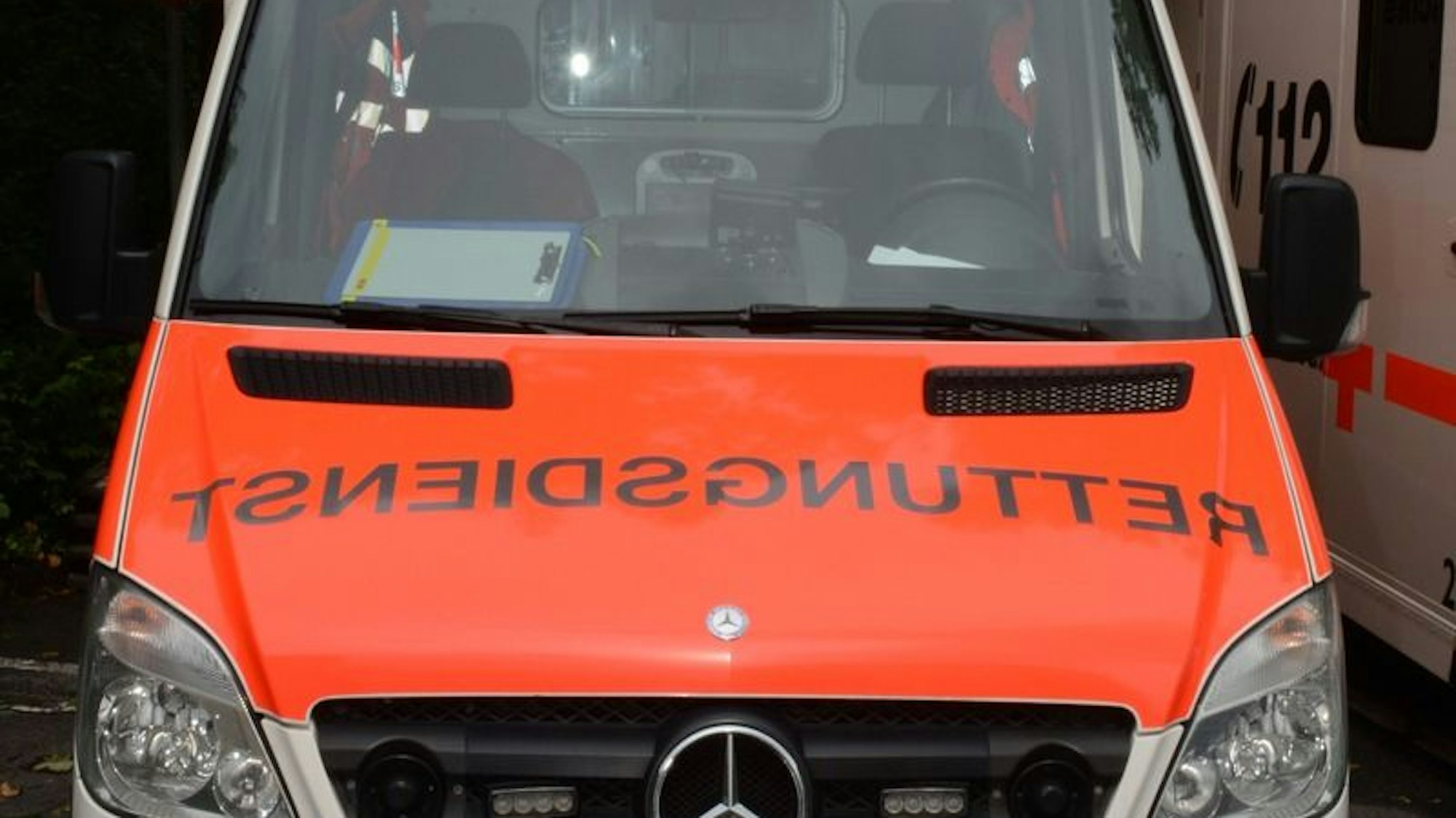 Zwei stark beschädigte Autos, ein Tesla und ein Mercedes, nach einem Unfall auf einer Straße.
