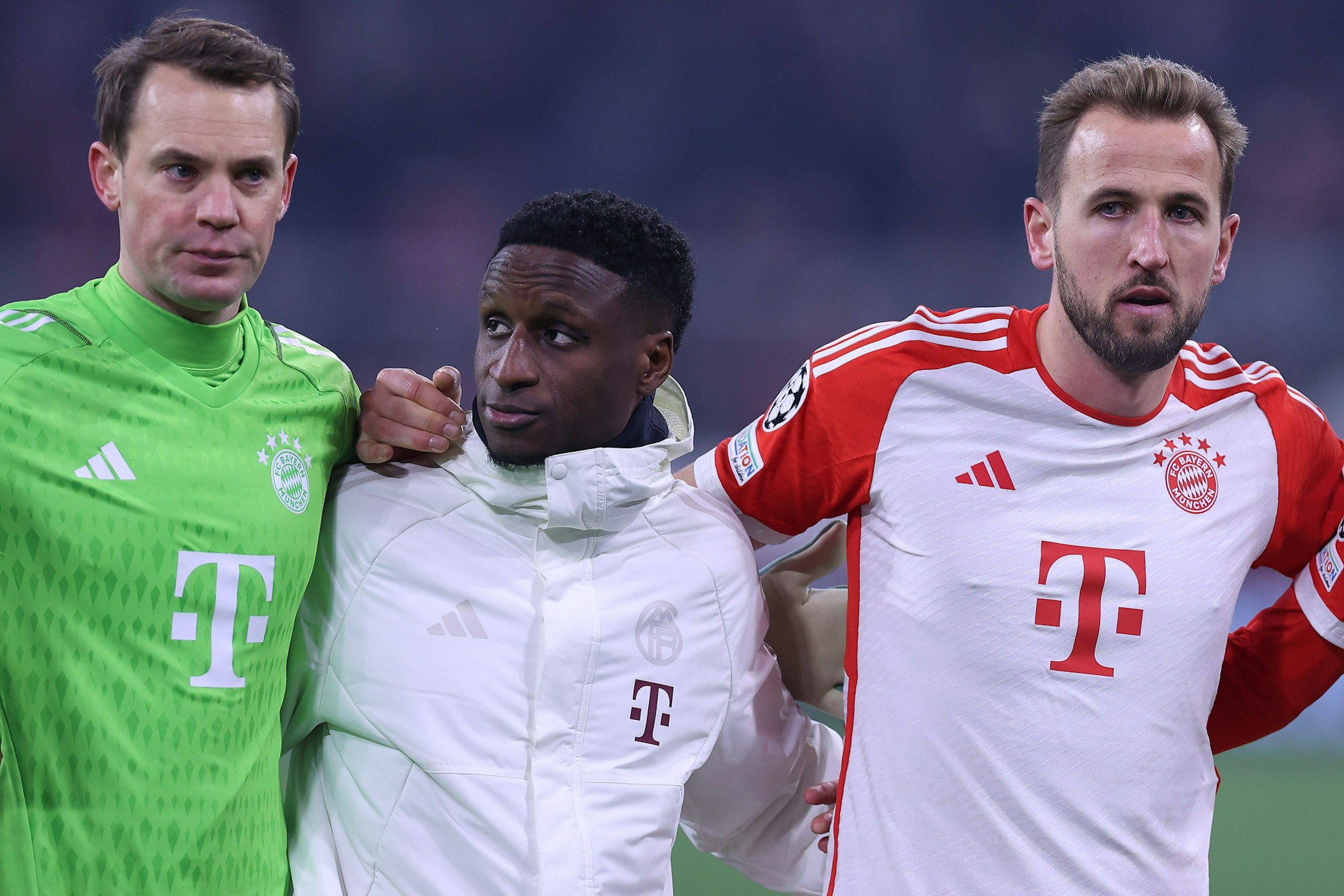 Bouna Sarr steht nach einem Spiel in Trainingsjacke zwischen Manuel Neuer und Harry Kane.