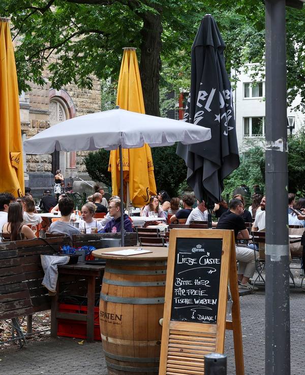Menschen sitzen draußen an Tischen.