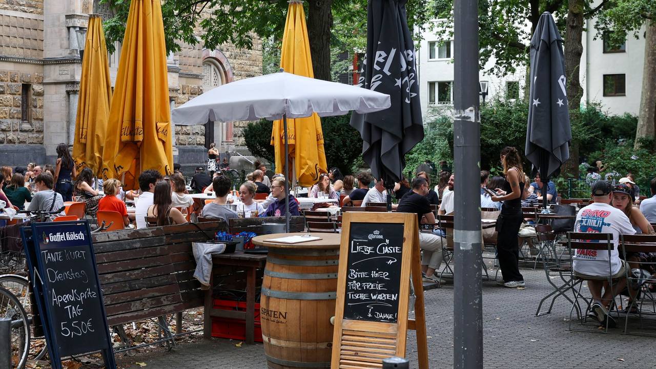 Menschen sitzen draußen an Tischen.