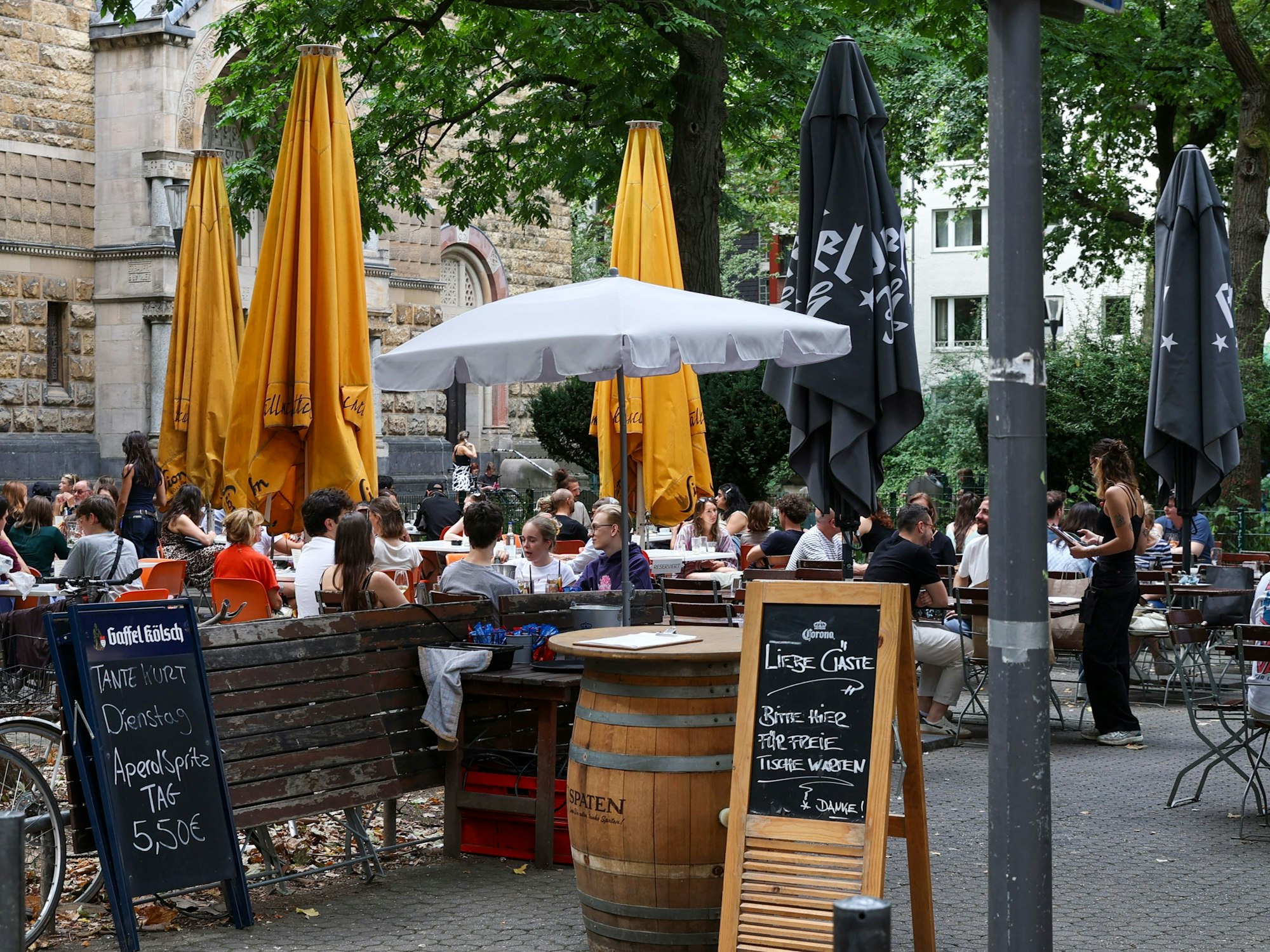 Menschen sitzen draußen an Tischen.