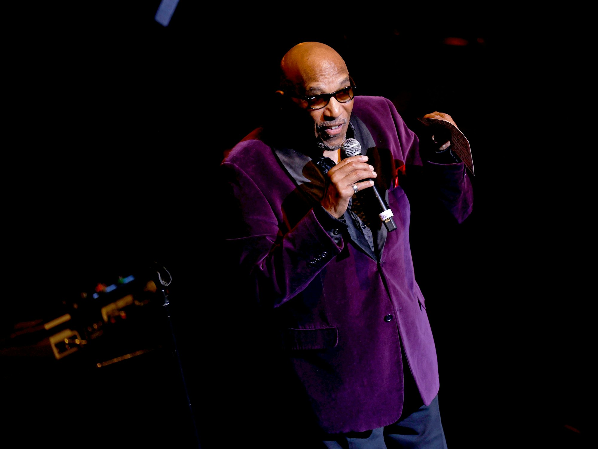 Ein Mann im lila Jacket spricht in ein Mikrofon