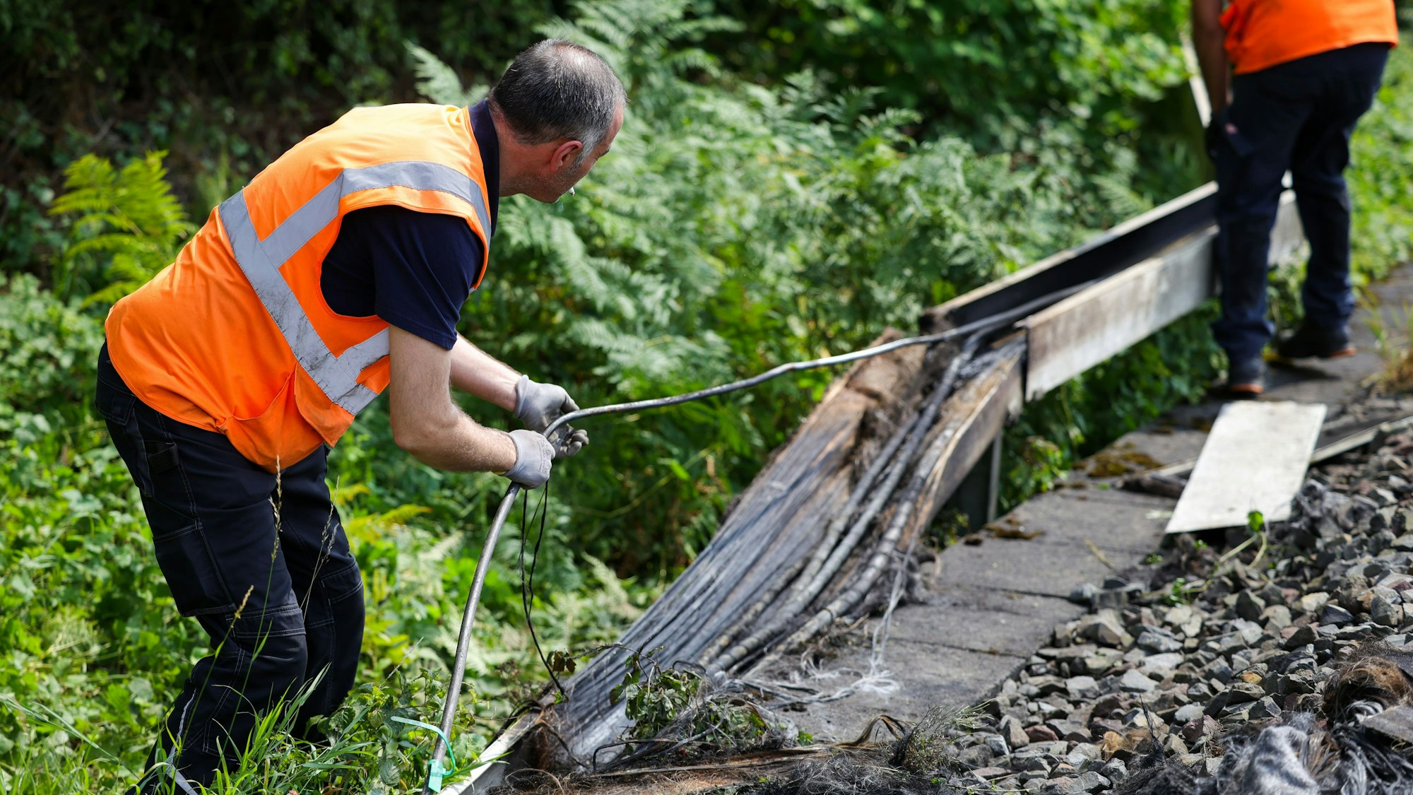 Mitarbeiter der Deutschen Bahn arbeiten an einem Gleisabschnitt in Düsseldorf. Dort wurde neben der Bahnstrecke Feuer in einem Kabeltunnel gelegt, der sechs Kabel in Mitleidenschaft zog.