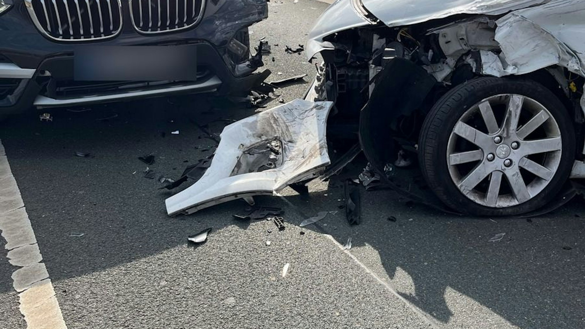 Zwei stark beschädigte Autos stehen nach einem Frontalzusammenstoß auf einer Brücke.