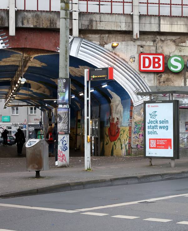 An einer Bahnunterführungen, die vollgeschmiert ist mit Graffiti, hängen Schilder.
