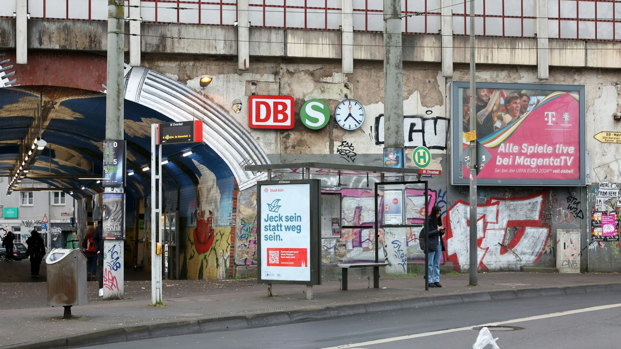 An einer Bahnunterführungen, die vollgeschmiert ist mit Graffiti, hängen Schilder.
