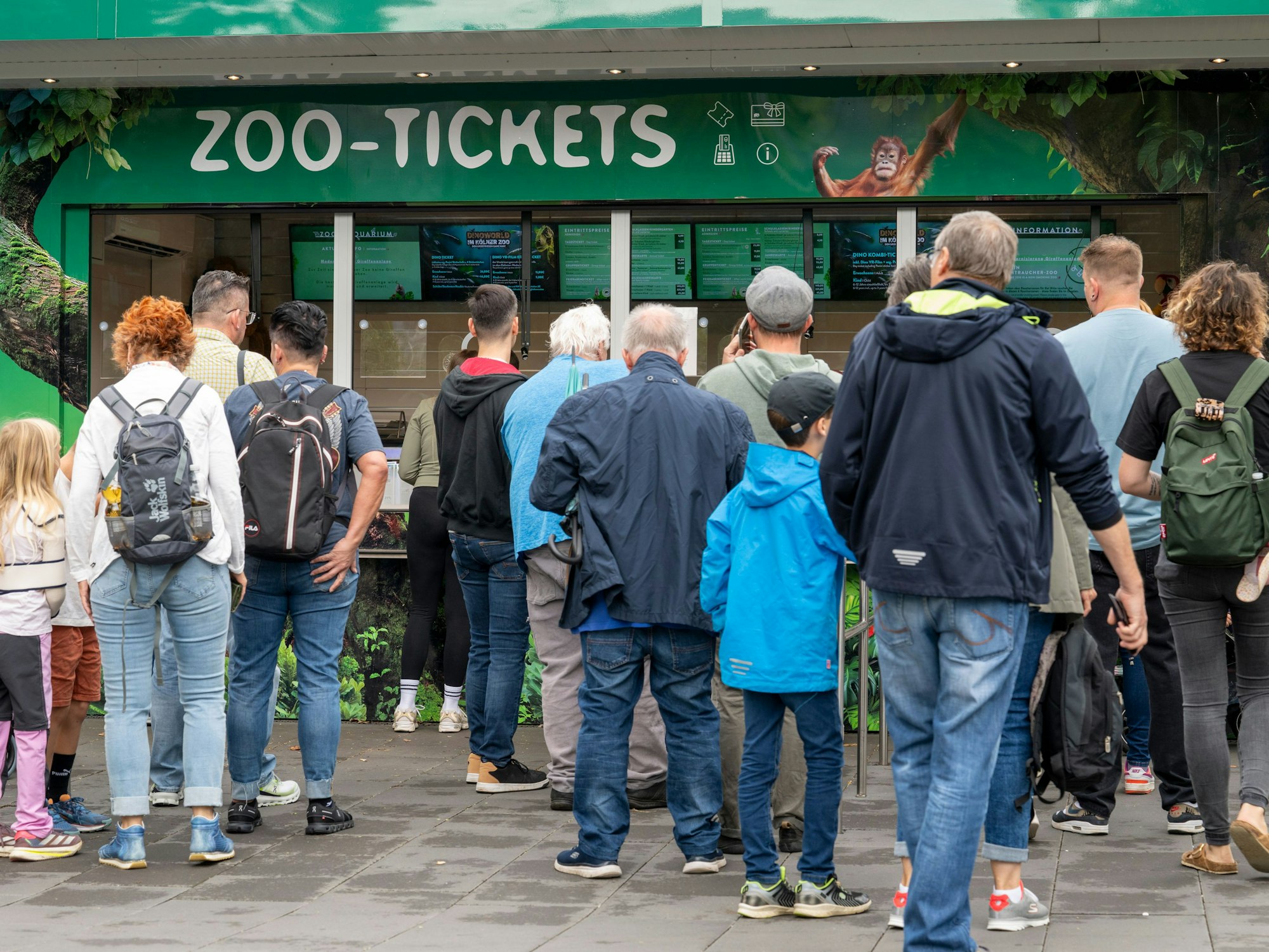 Menschen stehen vor einem Häuschen mit der Aufschrift Zoo-Tickets.