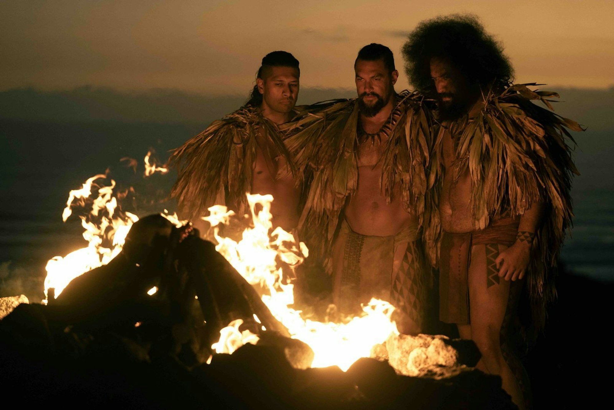 Beschwörung des Feuers, Beschwörung des Krieges: Te Kohe Tuhaka (links), Jason Momoa (zweiter von links) und Siua Ikale'o in der Apple-Serie „Chief of War“ über die frühe Geschichte Hawaiis. (Bild: Apple TV+)