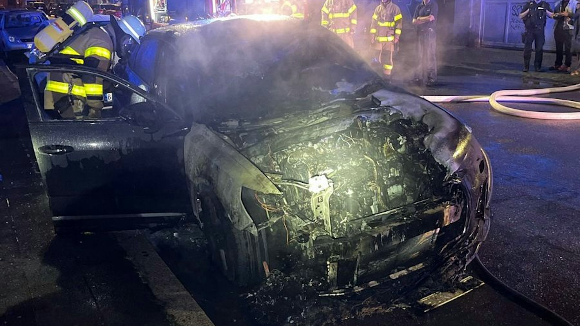 Ein ausgebranntes Auto steht am Straßenrand.