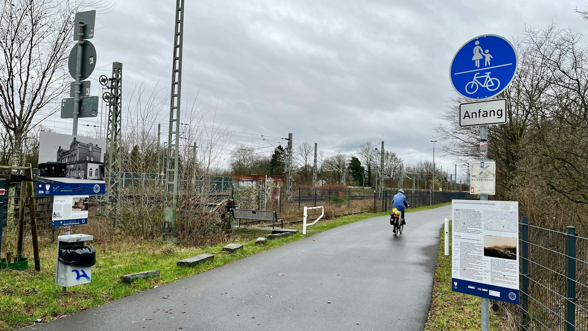 Ein Radfahrer radelt auf einem Asphaltweg lang.