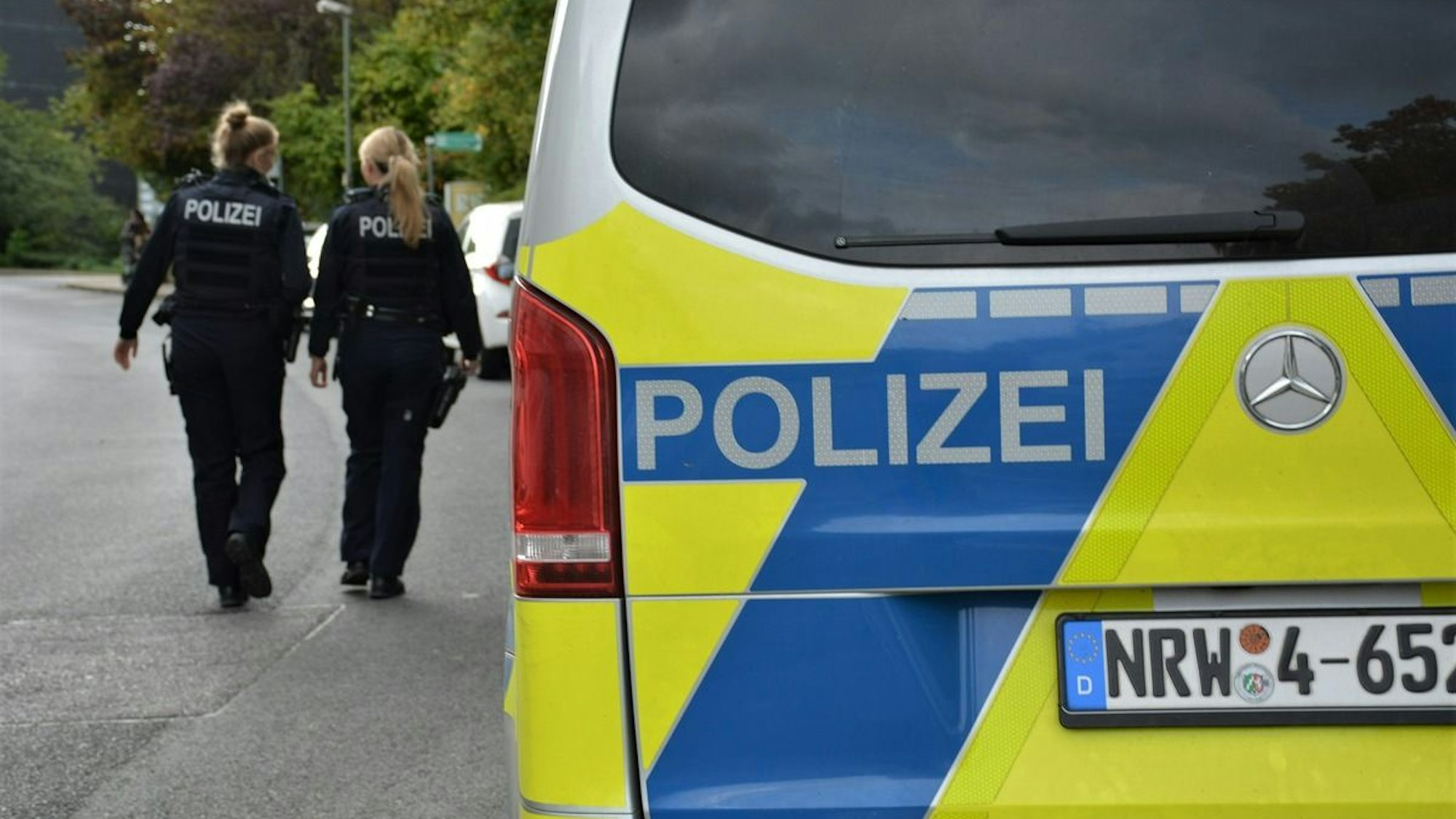 Ein Polizeiauto steht in einem Waldstück.
