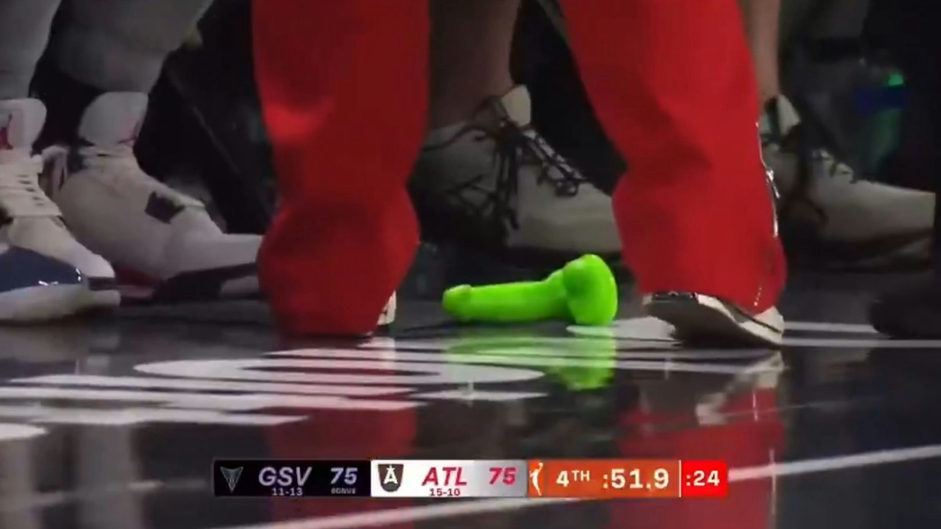 Ein grüner Dildo liegt auf dem Spielfeld.