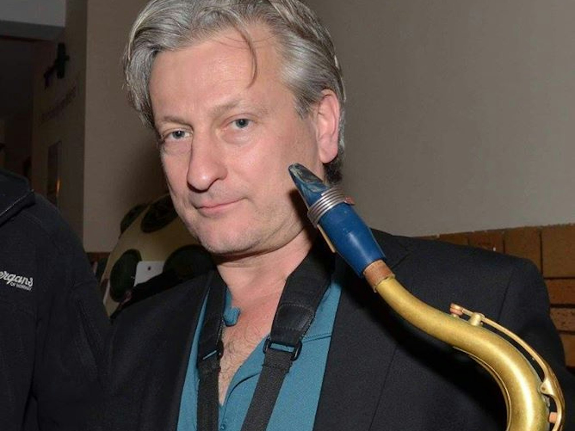 Ein Mann hält ein Saxofon in der Hand.