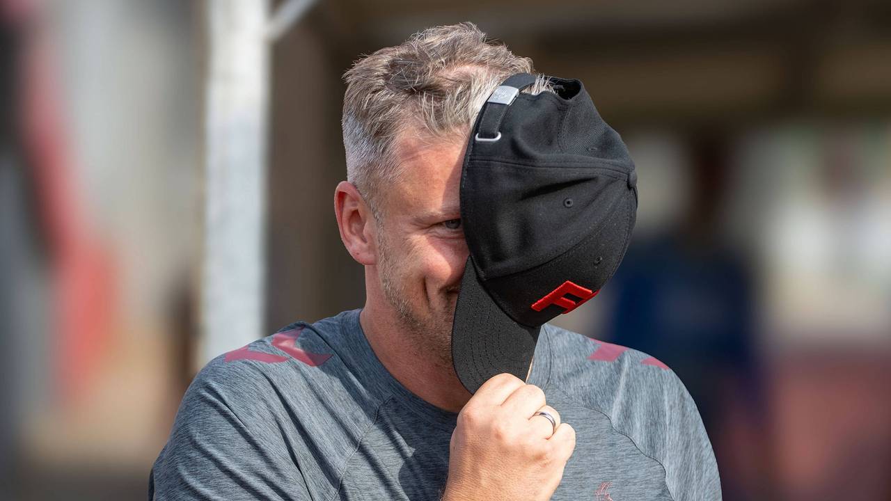 Lukas Kwasniok lächelt, während er sich die Mütze vor das Gesicht hält.