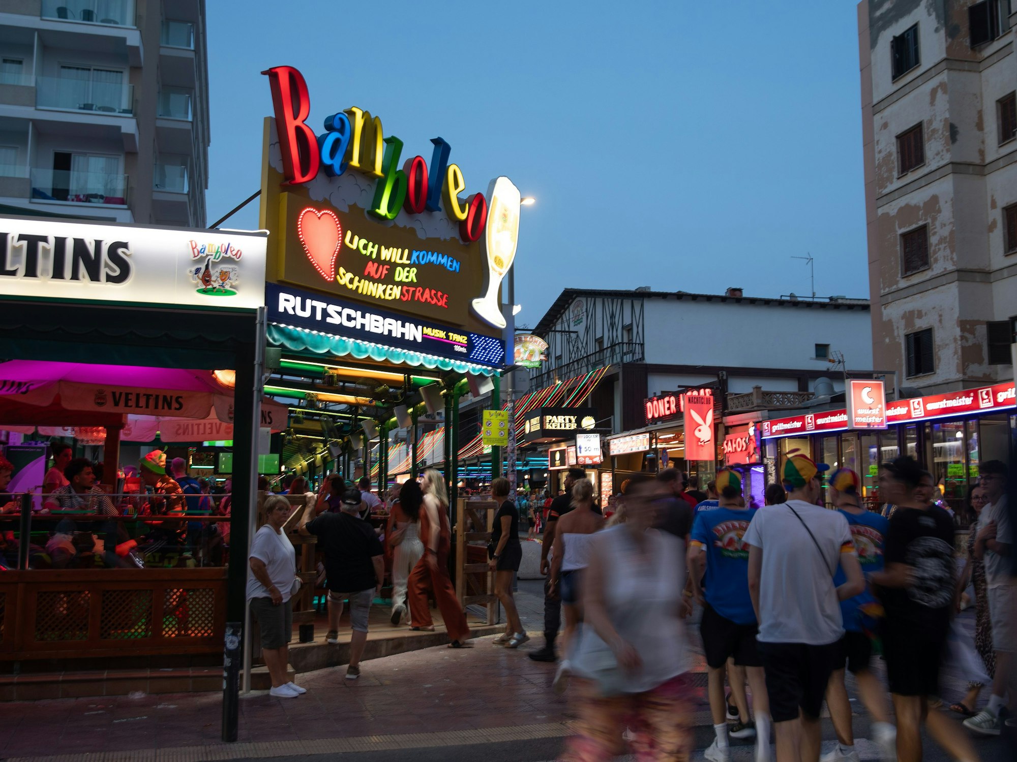 Menschen gehen neben der Schinkenstraße am Strand von Arenal auf Mallorca vorbei.