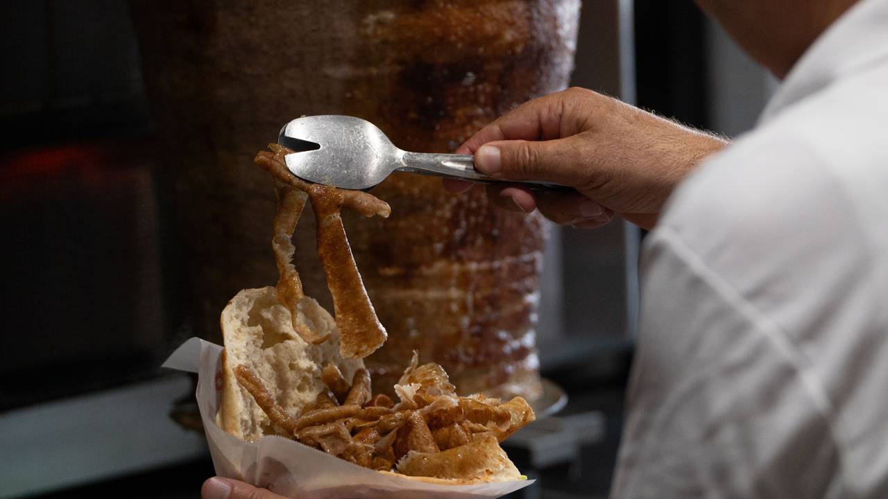 Ein Mann füllt ein Fladenbrot mit Fleisch von einem Dönerspieß. Der Spieß wurde von der Firma Birtat produziert.