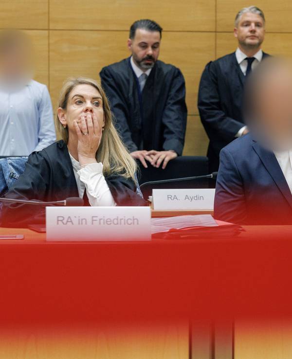 Zwei Angeklagte befinden sich mit ihren Verteidigern beziehungsweise ihrer Verteidigerin im Gerichtssaal.